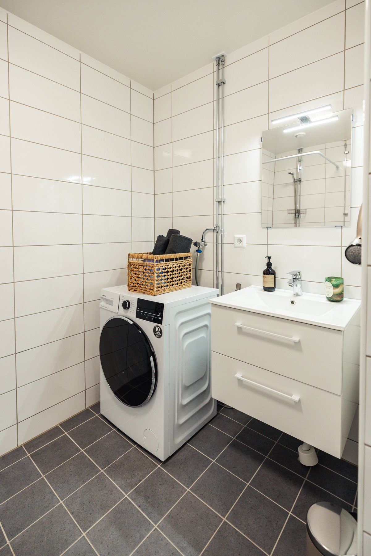 Badrum med tvättmaskin, handfat och spegelskåp